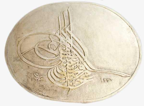 A off-white plaster oval with raised Arabic calligraphy