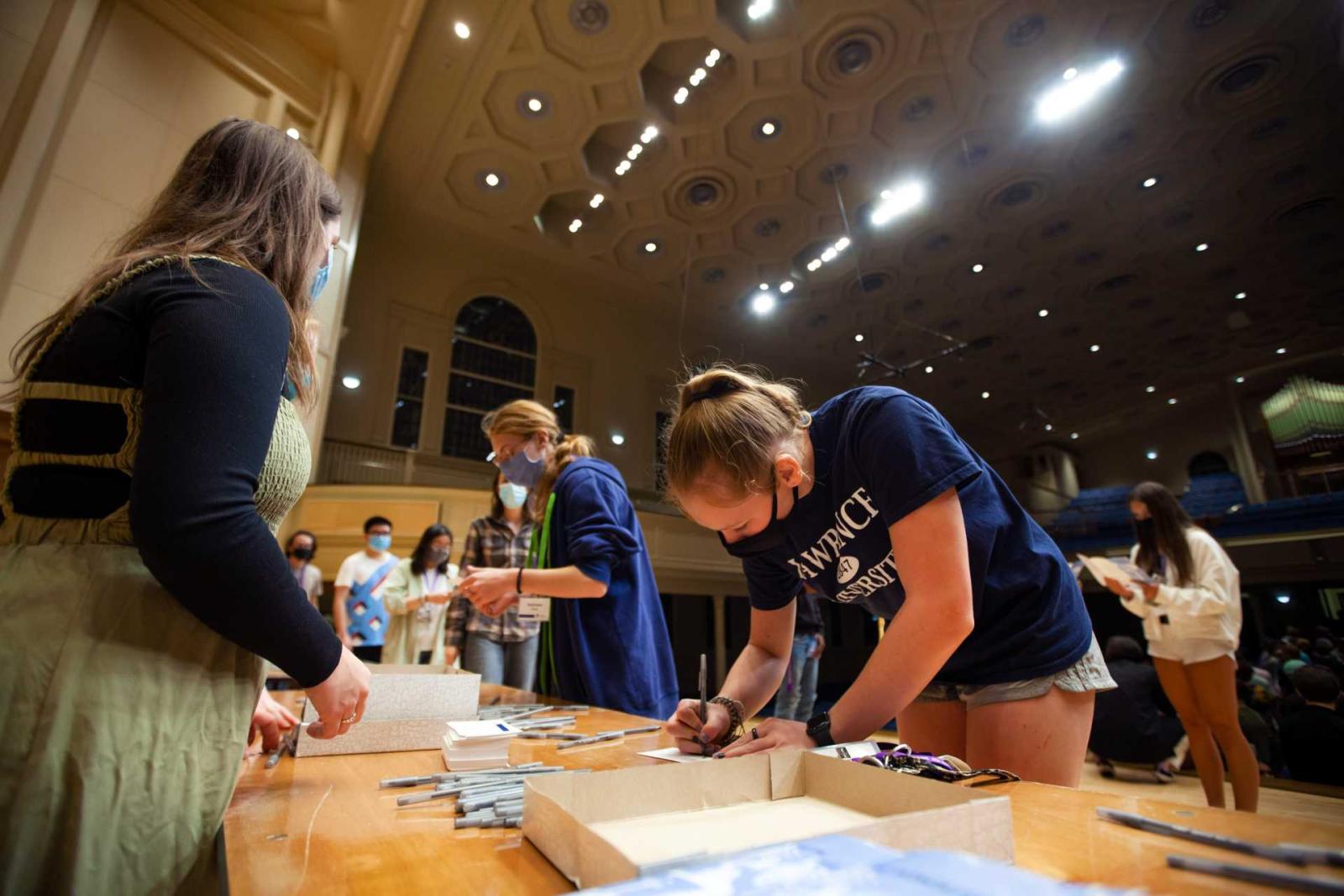 Student in Lawrence apparel signing Lawrence's Honor Pledge on the Memorial Chapel stage during the President's Handshake.