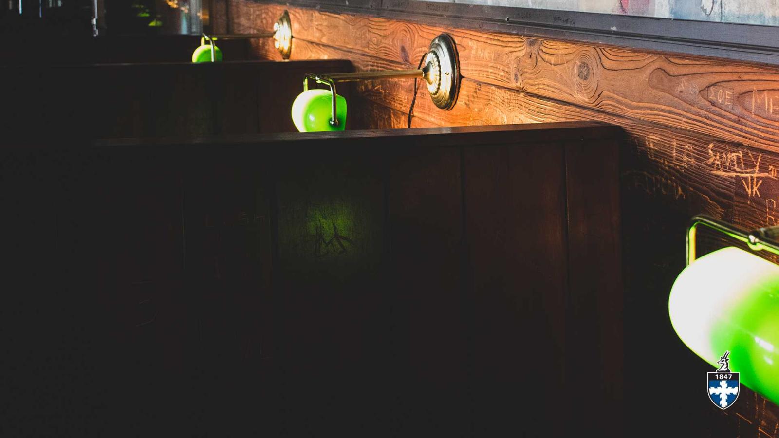 Close-up of green lamp above wooden booths.