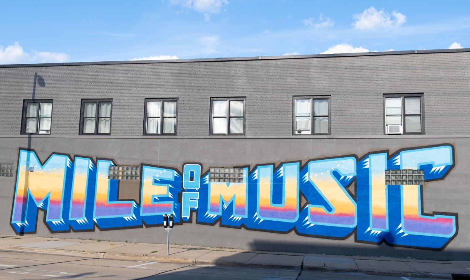 Mural of the words "Mile of Music" with blue, yellow, pin, and purple colors representing a sunrise