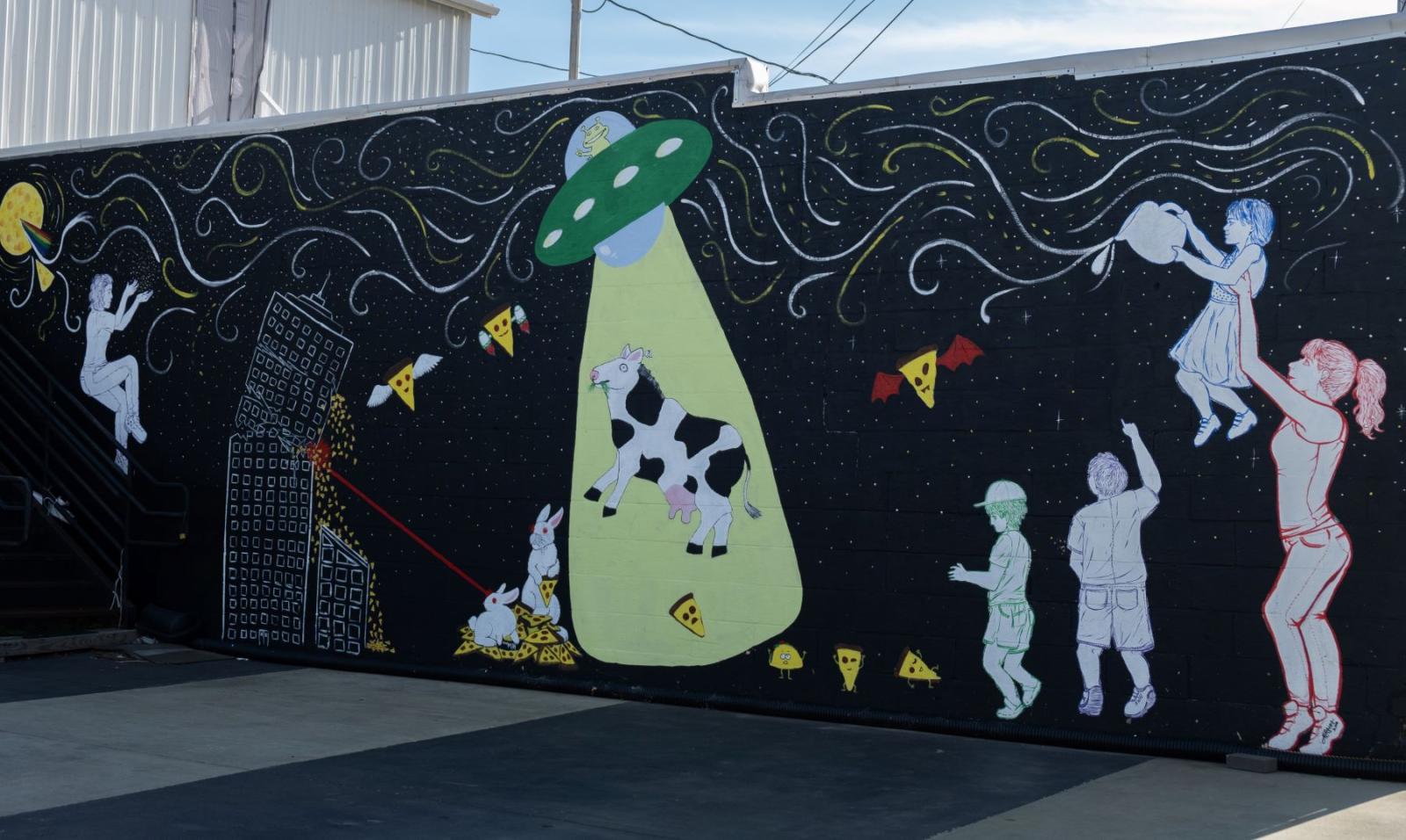 mural of space with a ufo and children playing
