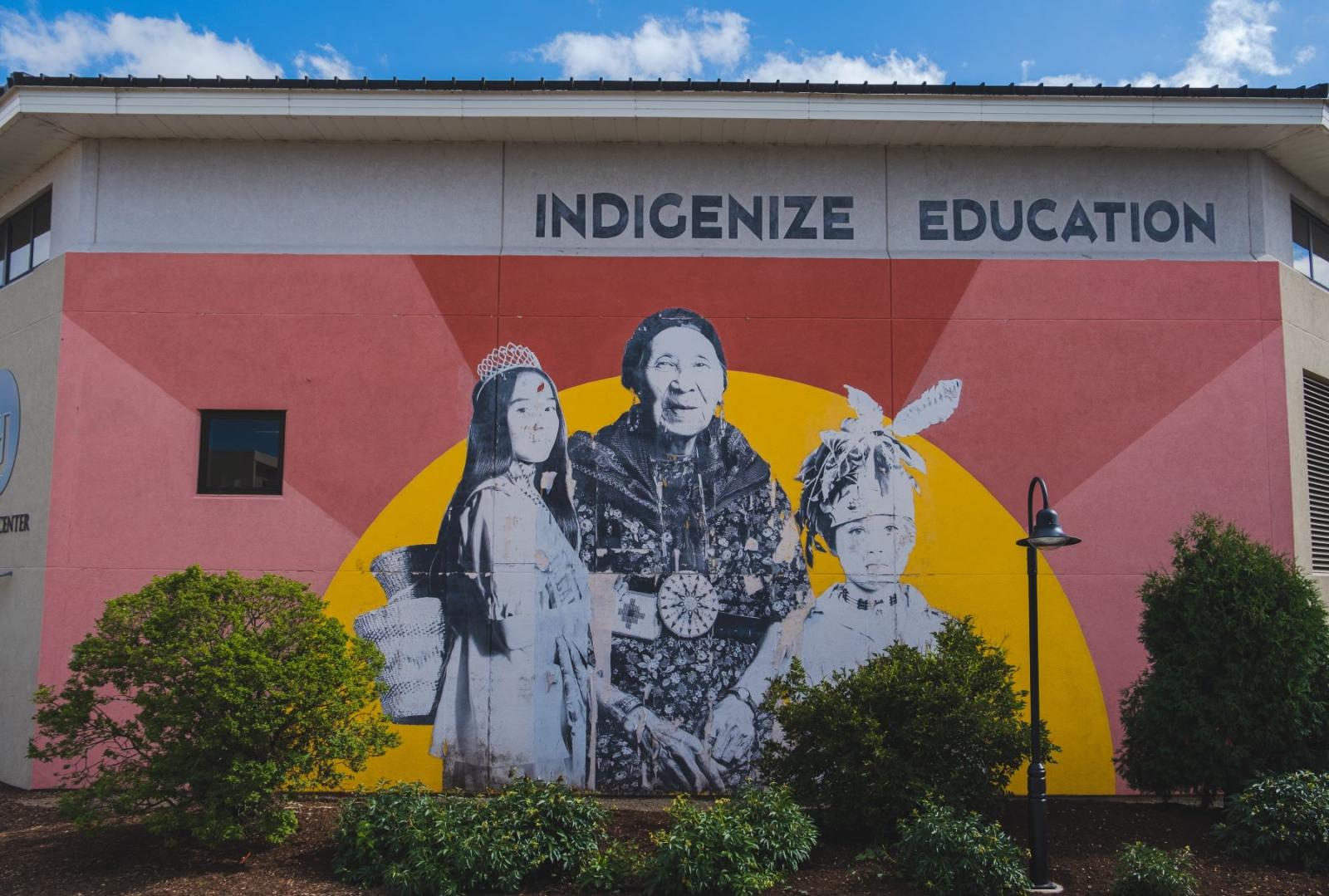 mural with three indigenous people with a background resembling the sunset