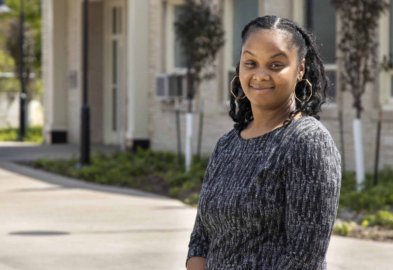 Brittany Bell, wearing a black and silver shirt, stands in front of Memorial Hall.