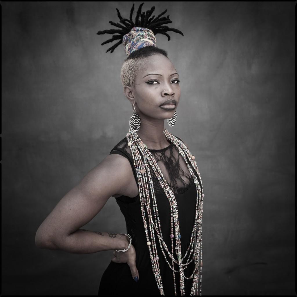 Performer Donet Gnahoré wearing a black dress with many necklaces and hands on hips.