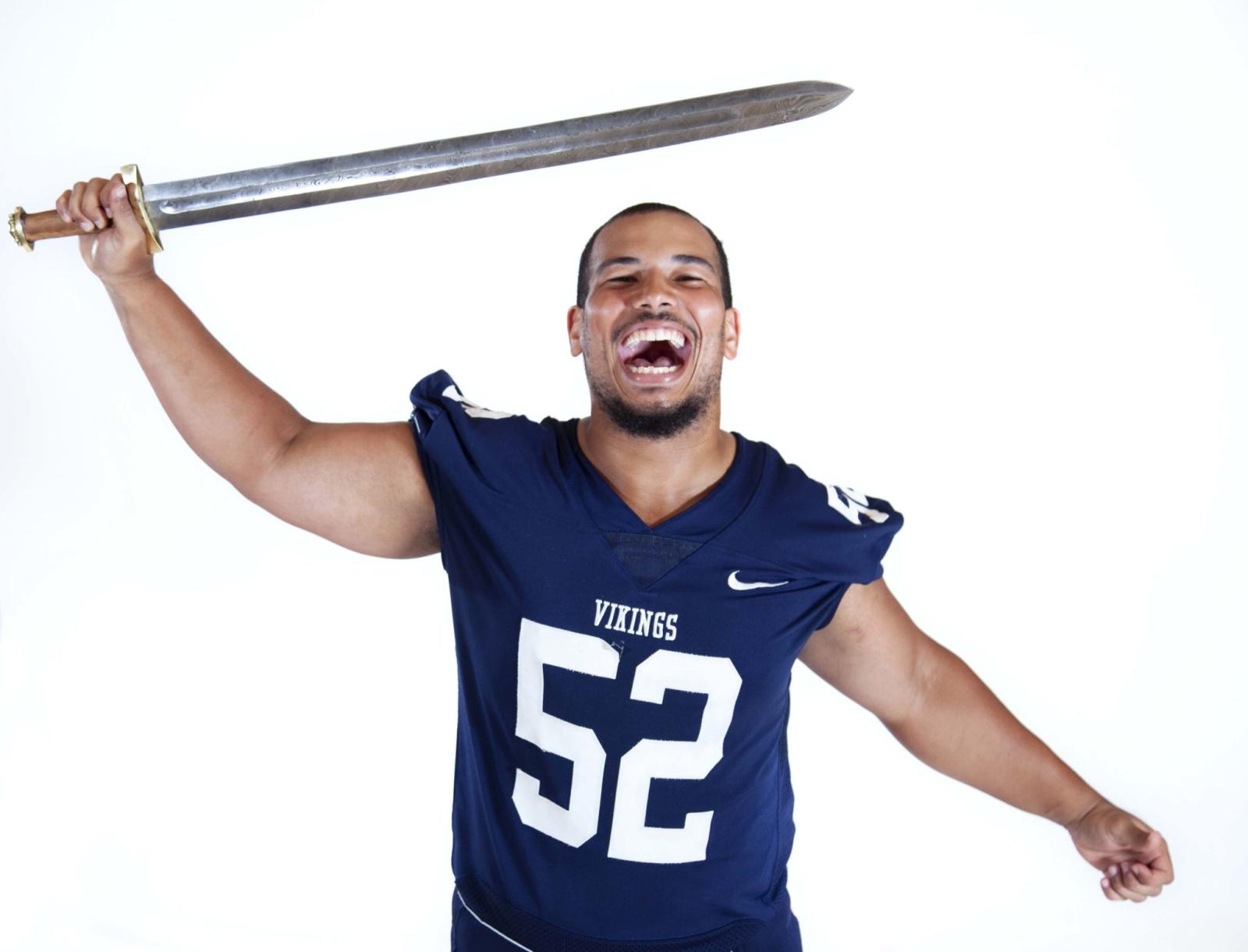 Football player Zachary Adams holds sword over his head