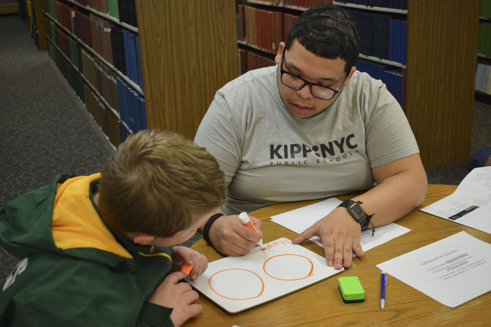 Lawrence student tutoring elementary student in library.