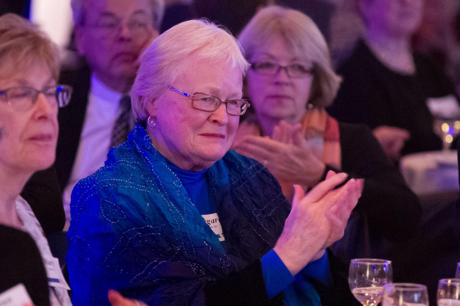 Margaret Carroll clapping while at a dinner banquet.