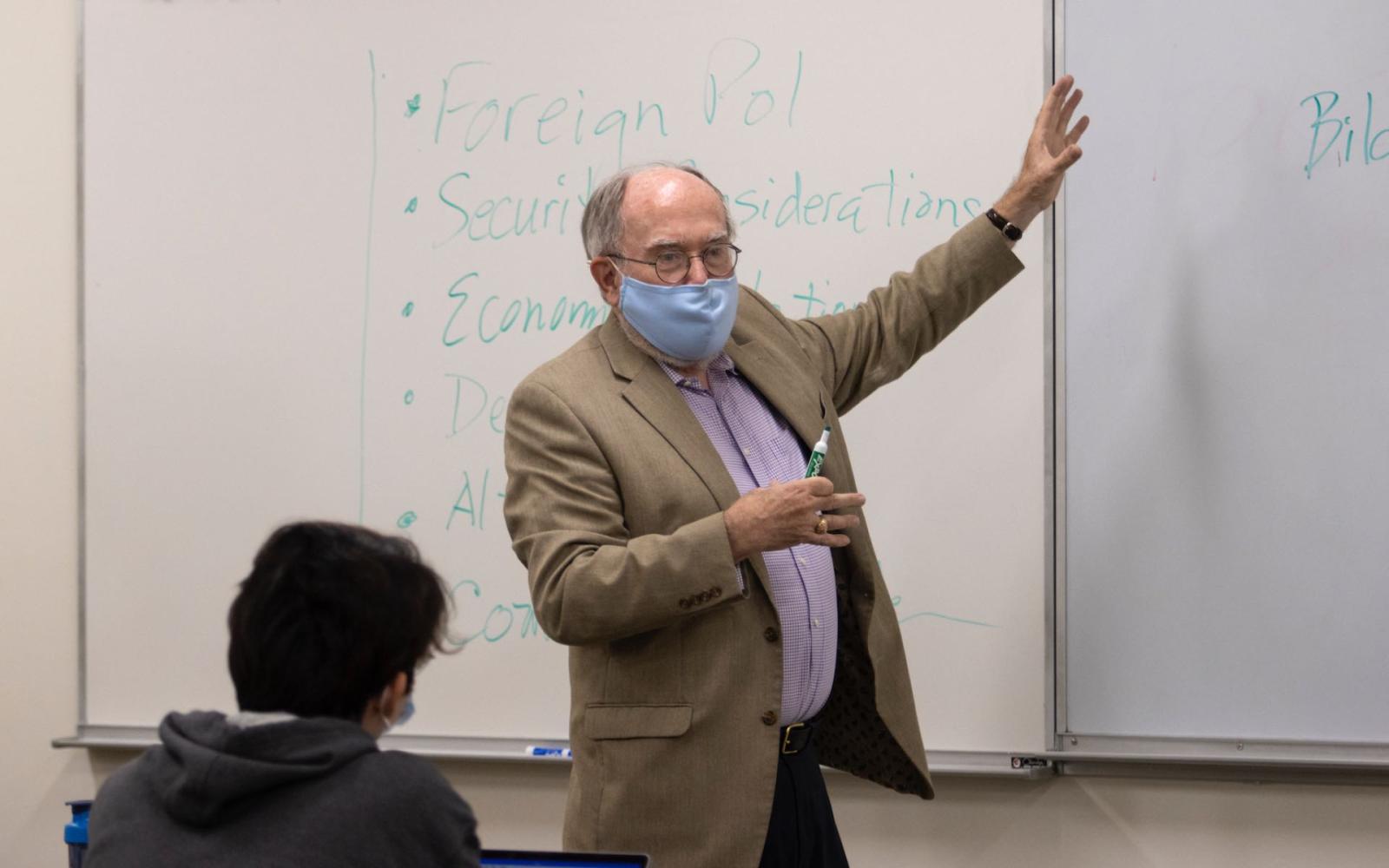 Shaun Donnelly, 2021's Visiting Scarff Professor, gestures towards the whiteboard with dry erase marker in hand.