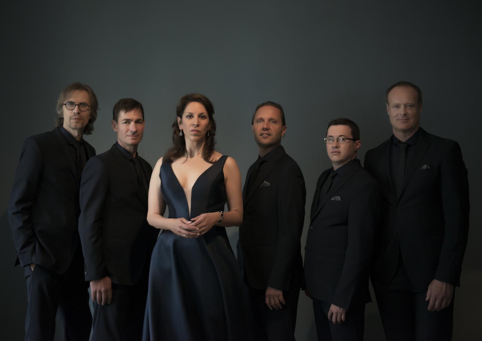 Musicians of performing group Singer Pur standing in a line in front of a grey background.