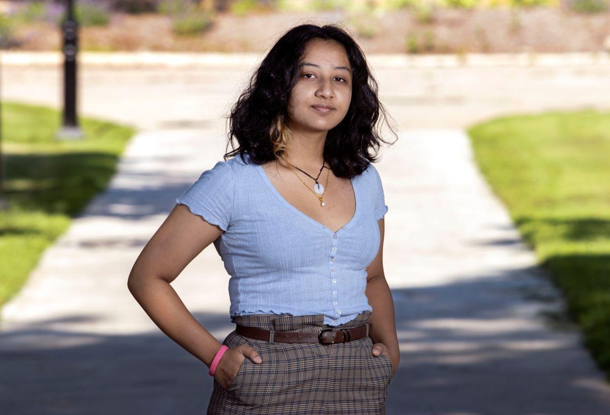 Tee Karki, wearing a purple shirt, poses on Main Hall Green.