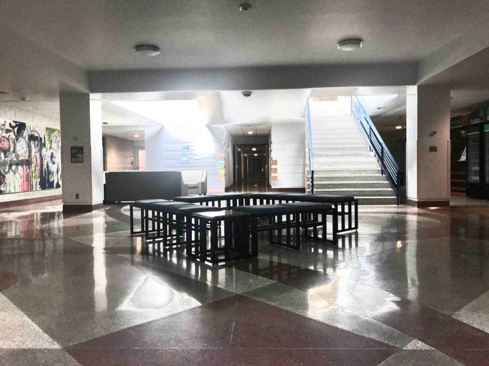Pile of black benches in the middle of a lobby inside the Conservatory of Music building.