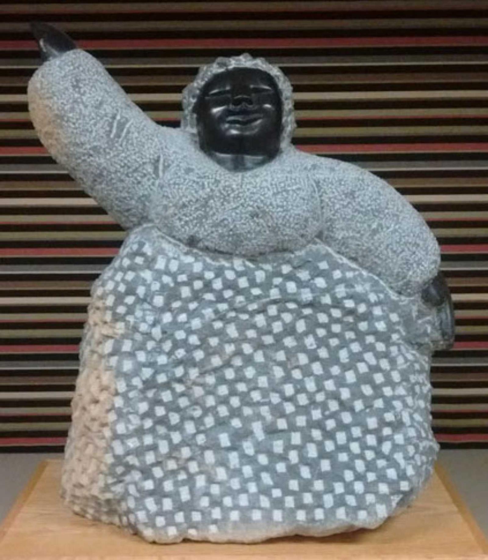 A stone sculpture of a woman waving her right hand above her head.