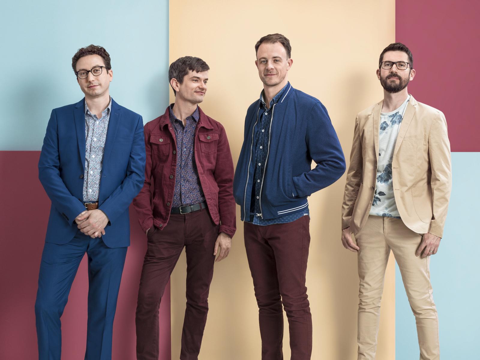 Performing group Third Coast Percussion standing in front of a geometrically colored wall.