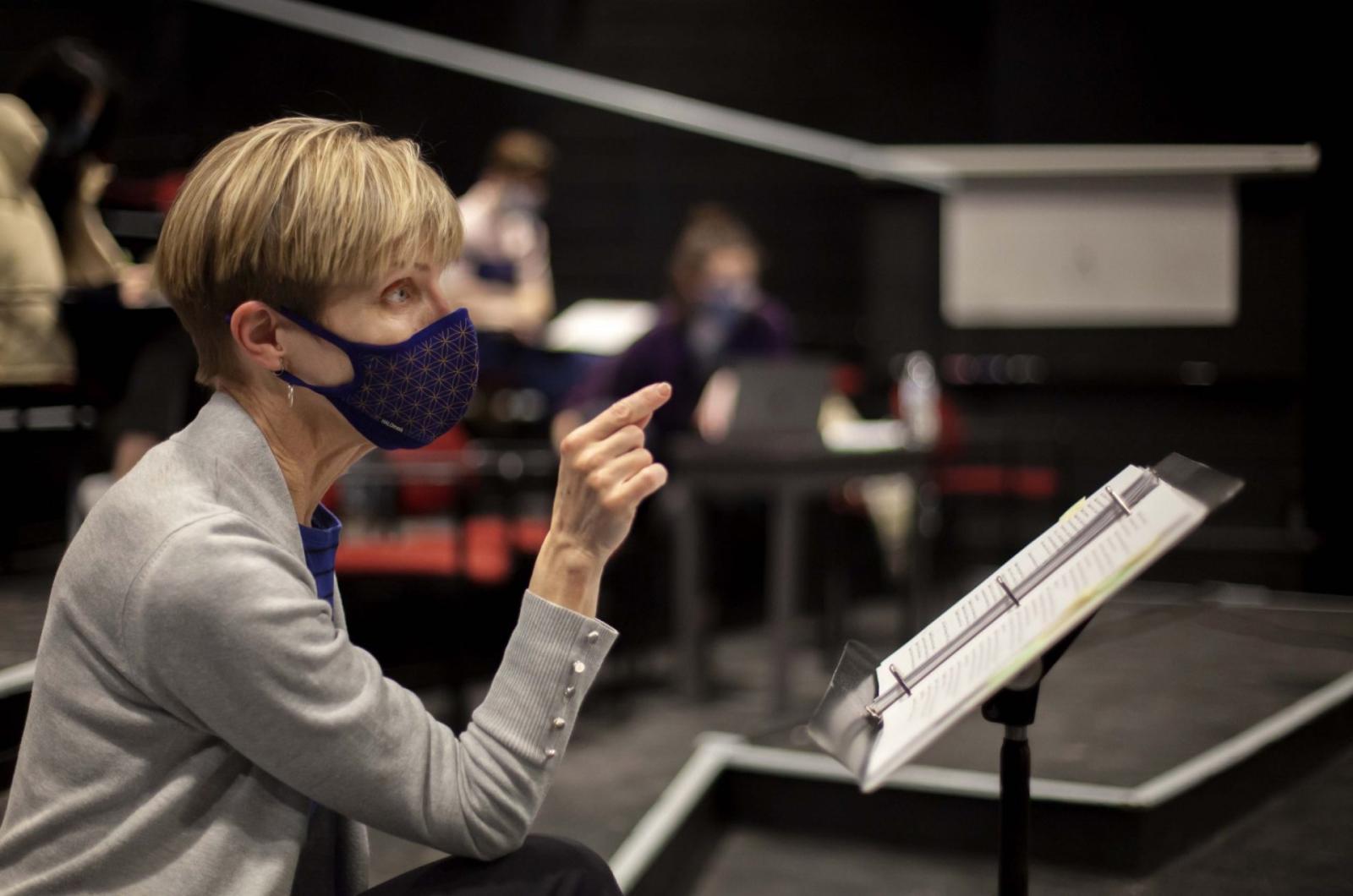 Kathy Privatt seats in the audience behind a music stand gives notes.