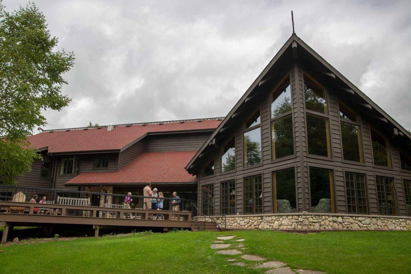 Guests relax on the deck of the main lodge during a 2019 summer seminar at Bjorklunden.
