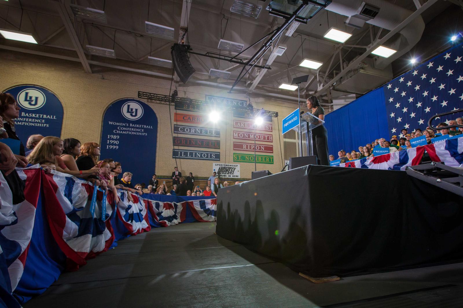 Michelle Obama speaks from a stage in Alexander Gym as a crowds leans forward.