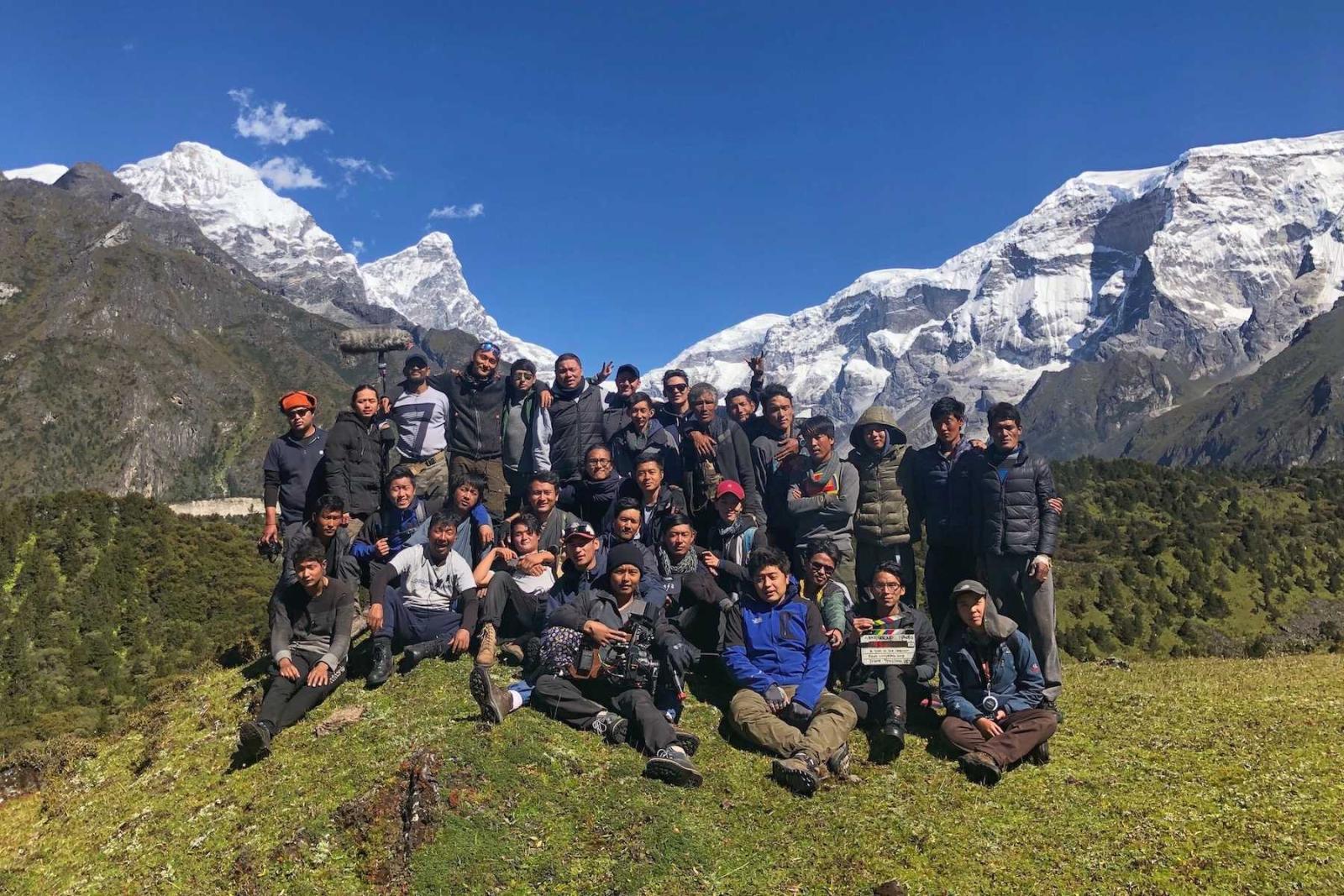 The film crew poses for a group photo with mountains in the background.