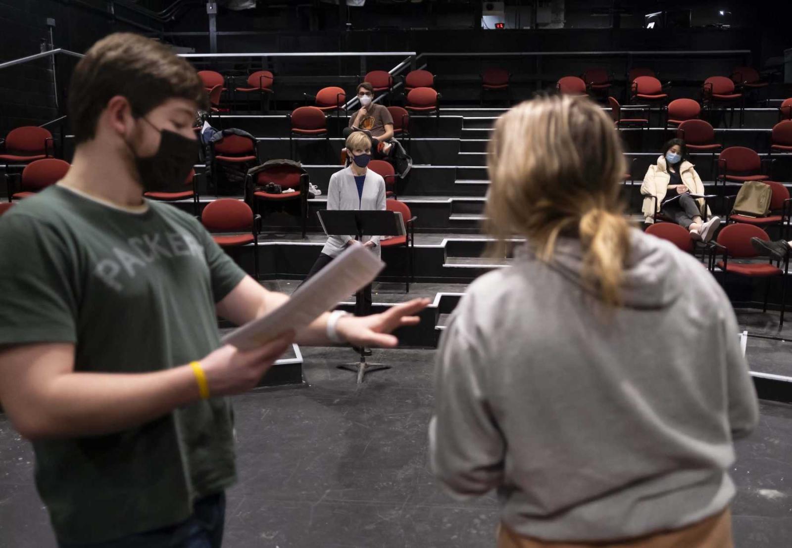Kathy Privatt watches from the front of the stage as Alec Welhouse, a junior, and Nina Broberg, a sophomore, read lines from a script in Cloak Theatre..