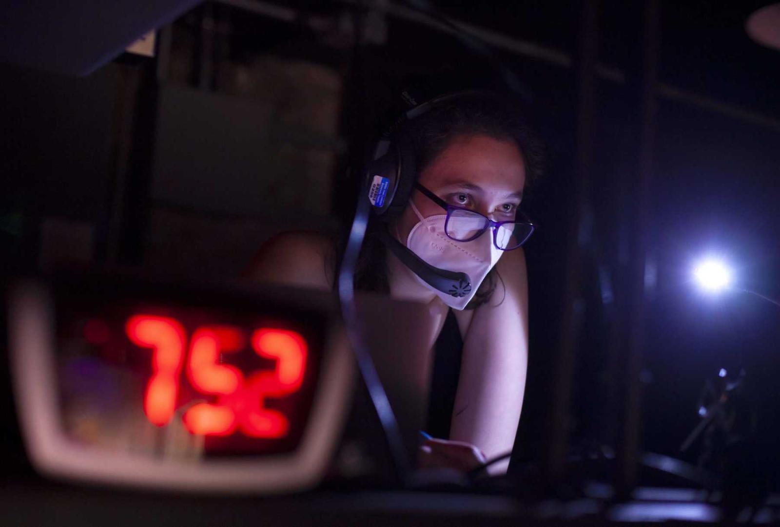 Nihan Baysal, a sophomore, wears a headset as she watches rehearsal from the control booth.