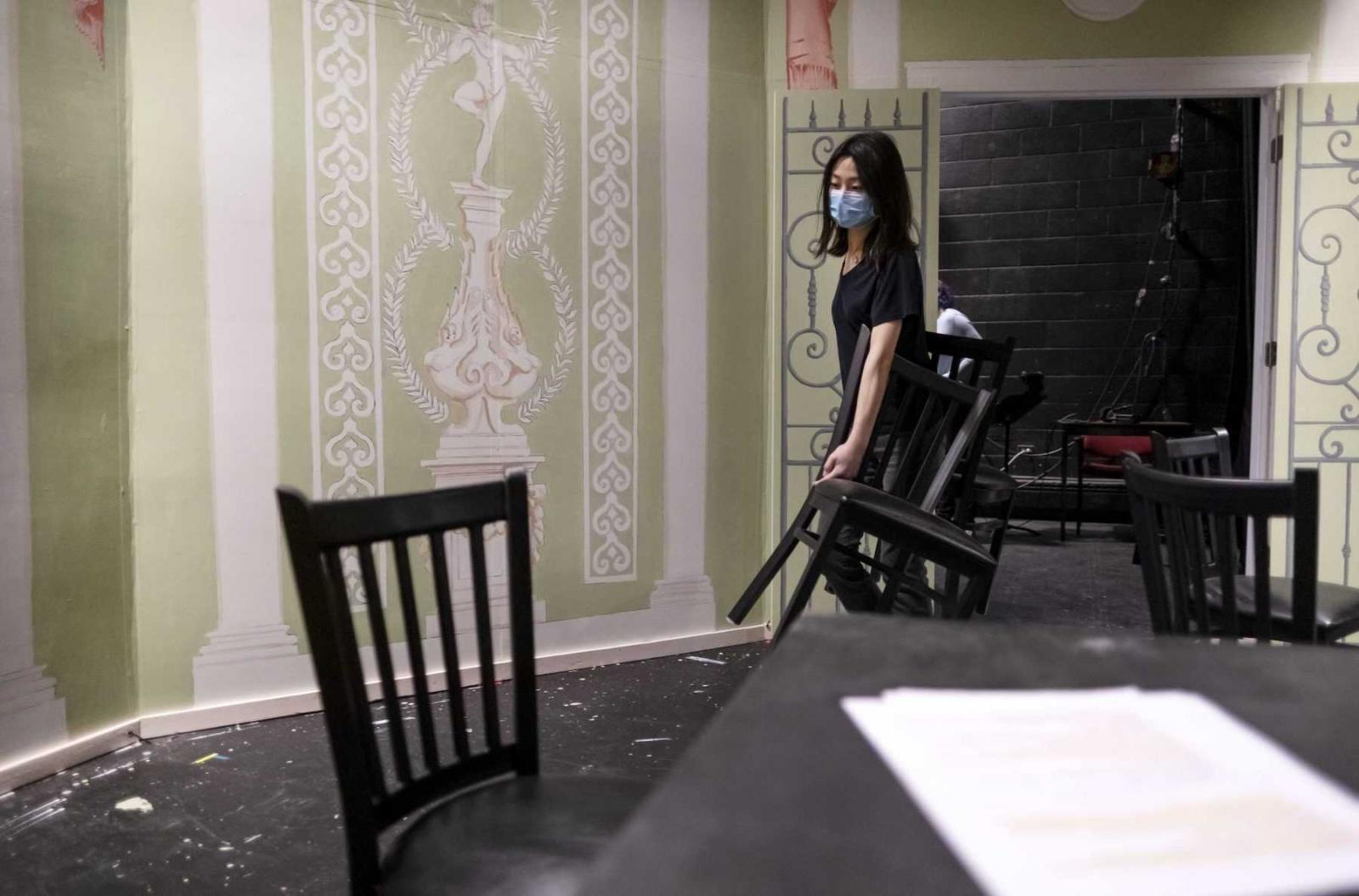 Lulu Wang, a junior, carries a chair as she gets the stage ready for a scene change during rehearsal in the Cloak Theater.