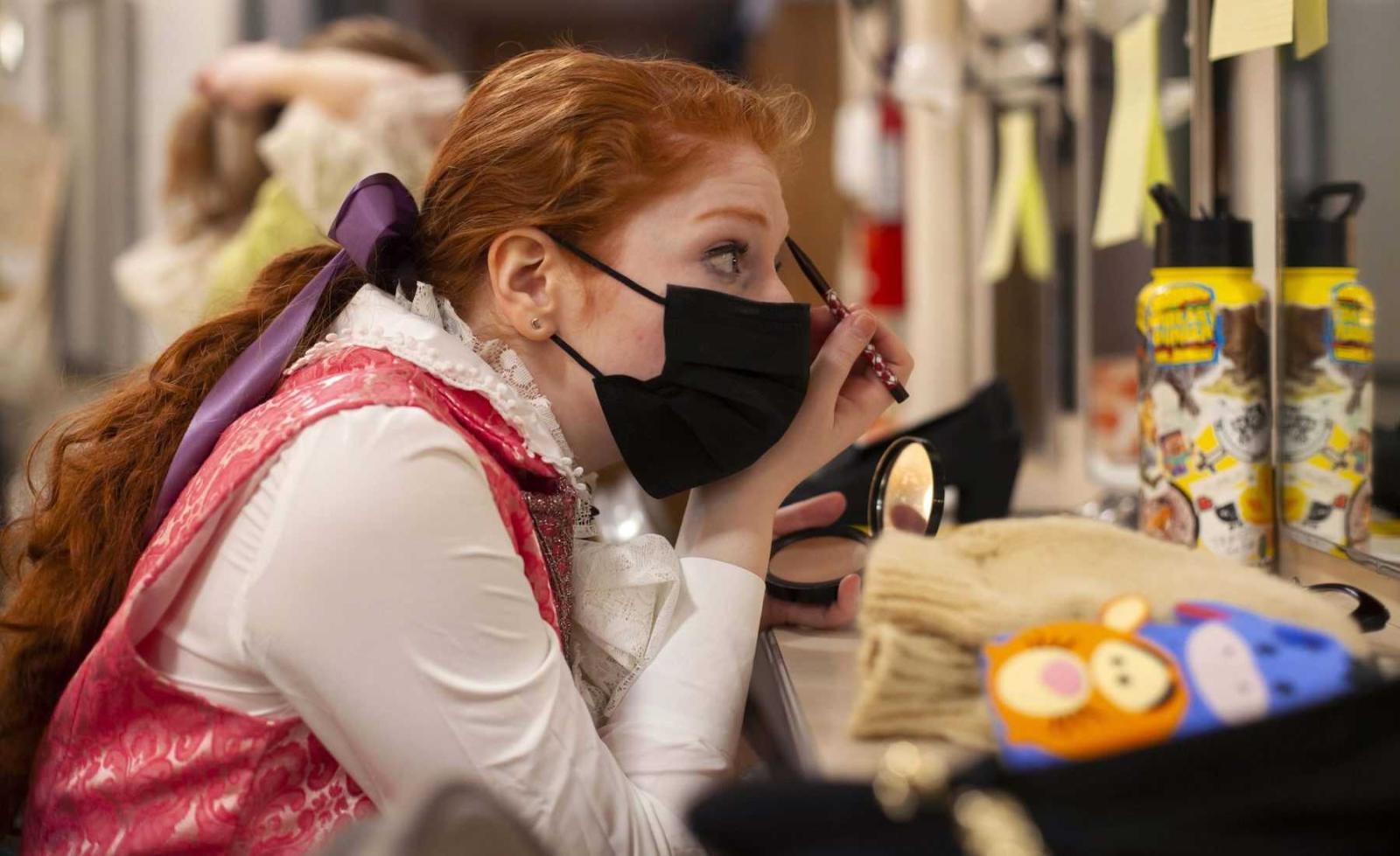 Frankie Sobel, a junior, puts on eye makeup while looking into a mirror before rehearsal.