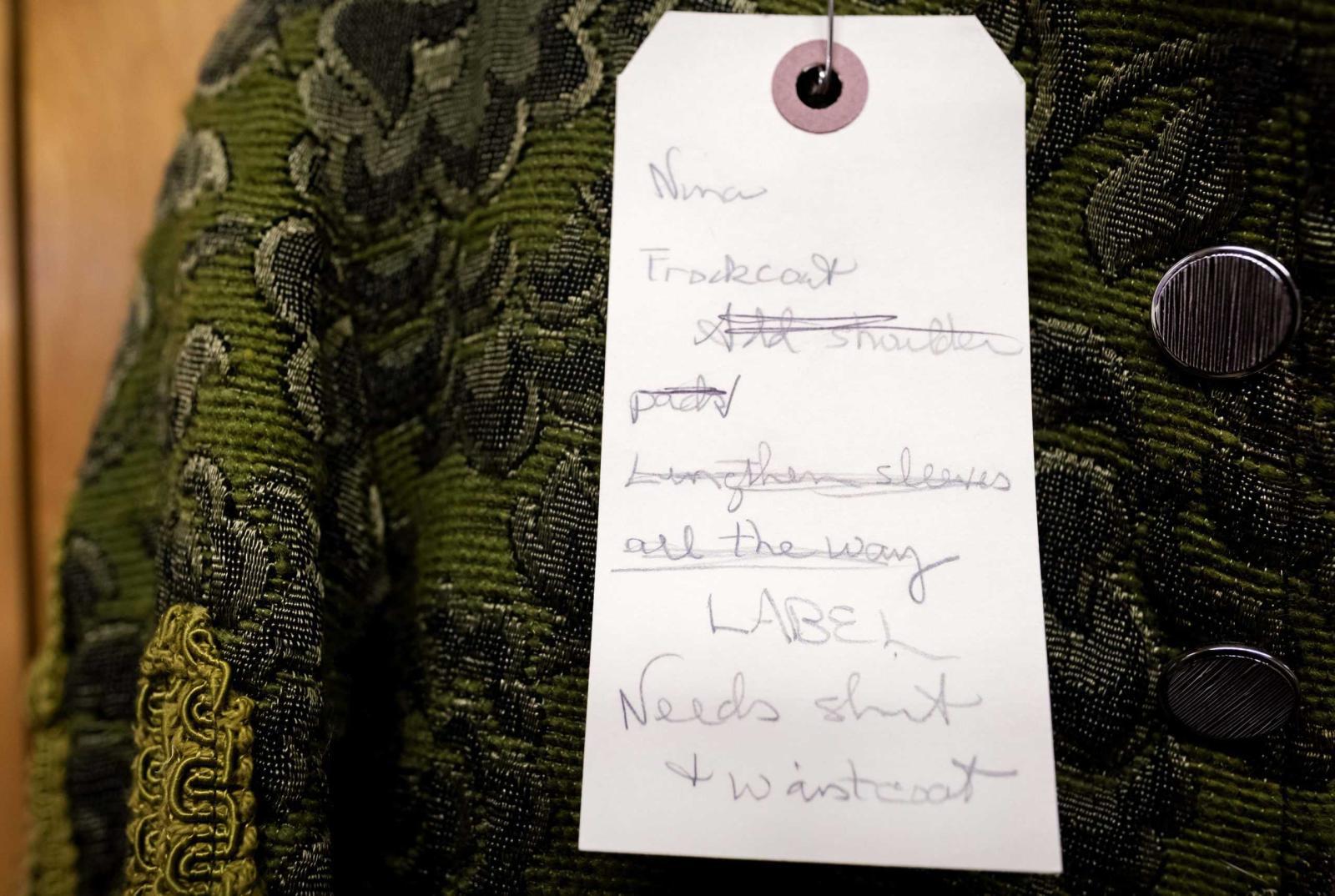 Notes for a costume that will be used for Molière Inspired are written on a label and attached to the costumes.