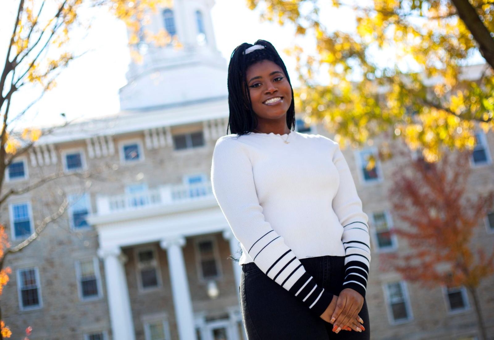 Kelsi Bryant standing outside Main Hall on a sunny fall day.