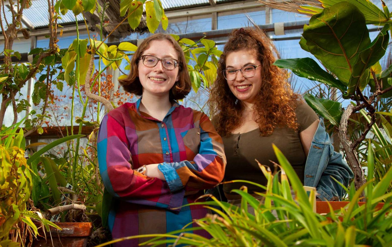 Lauren Kelly and Emma Zelles stand for a portrait in the Briggs Hall Greenhouse.