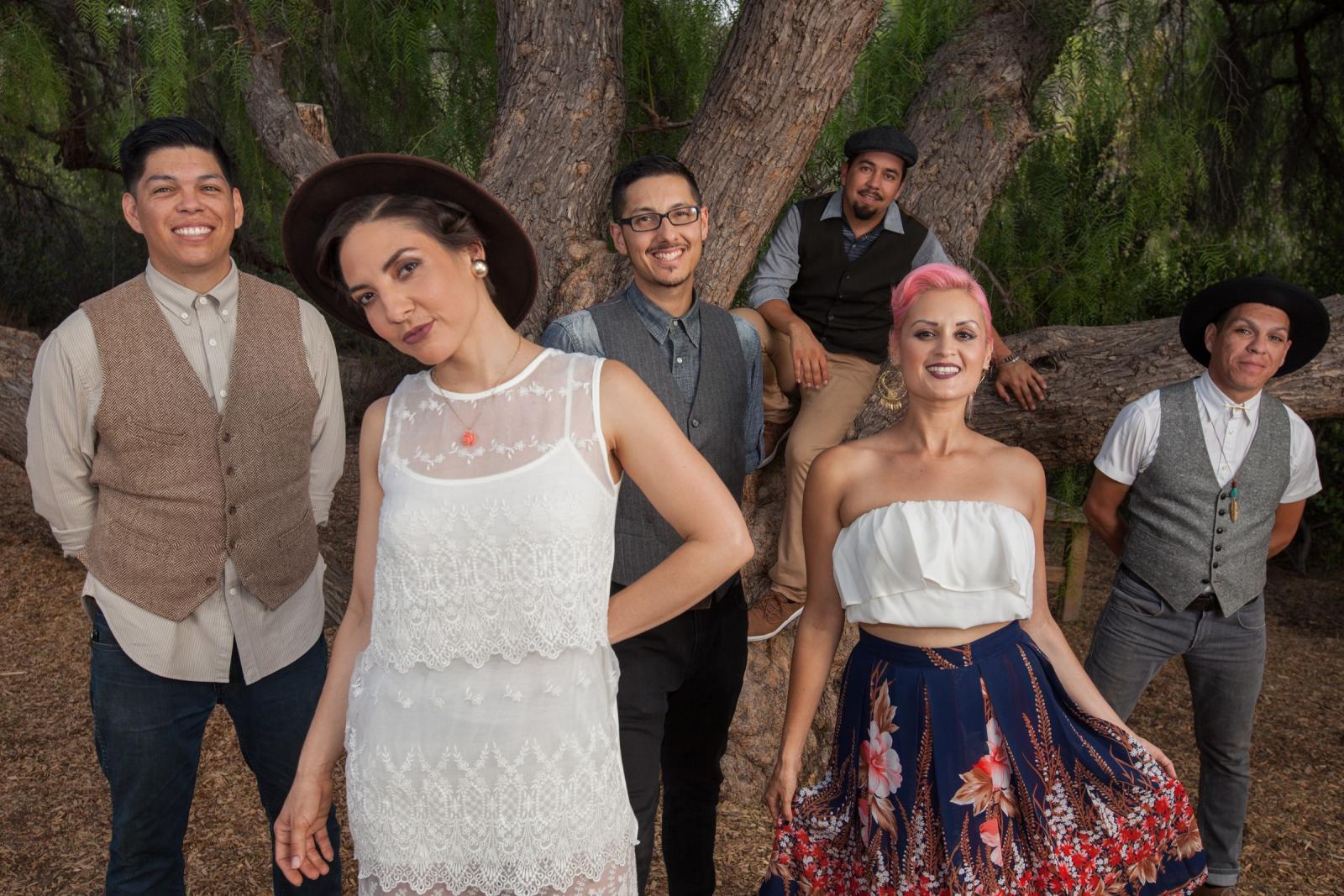 Performing group Las Cafeteras posing in front of a large tree