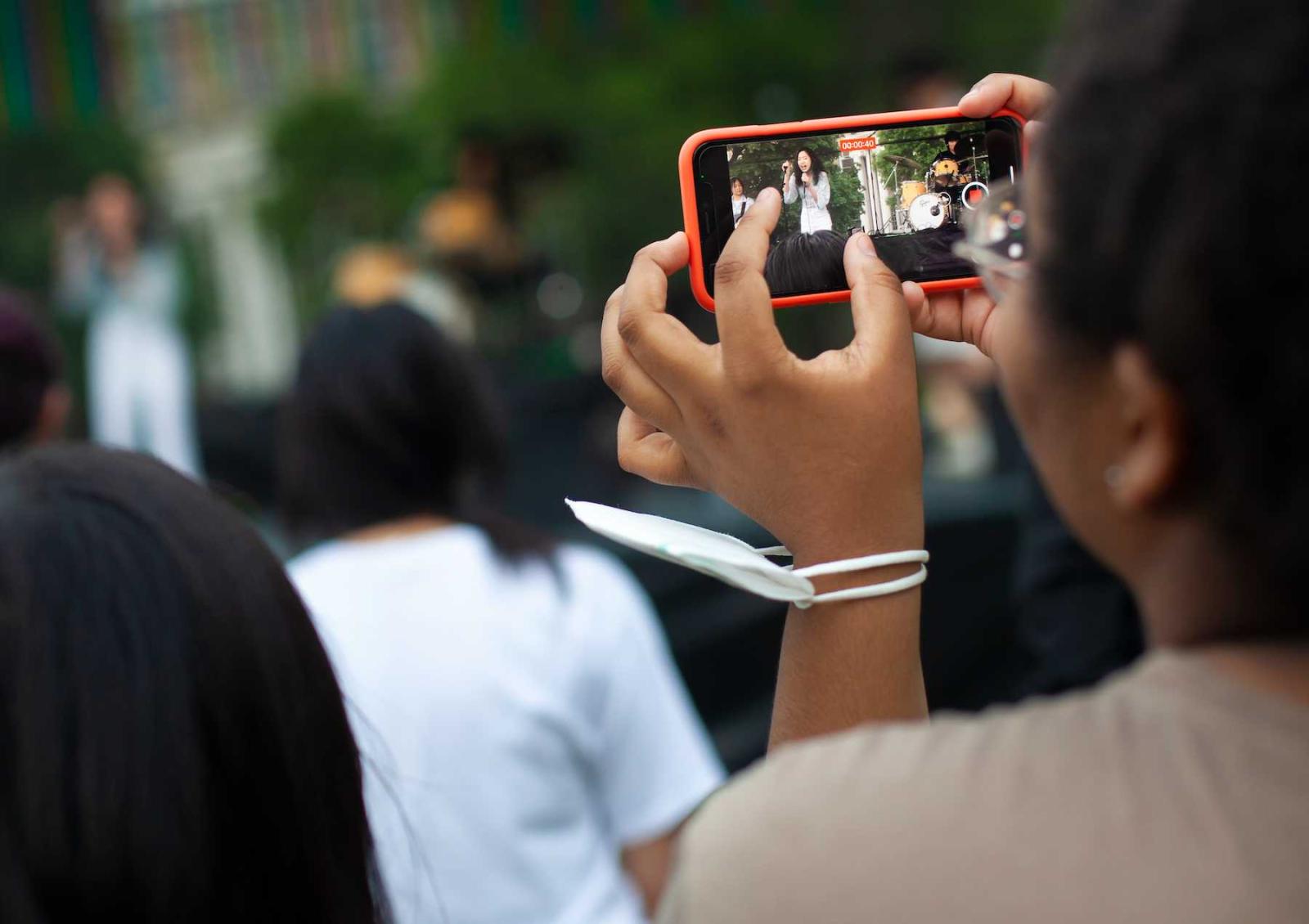 A student captures an image on a cell phone during an LUaroo performance.