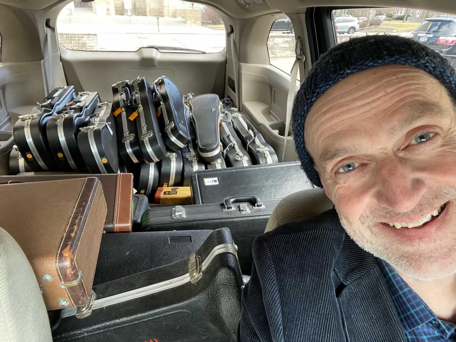 Brian Pertl takes a selfie with a van full of donated musical instruments.