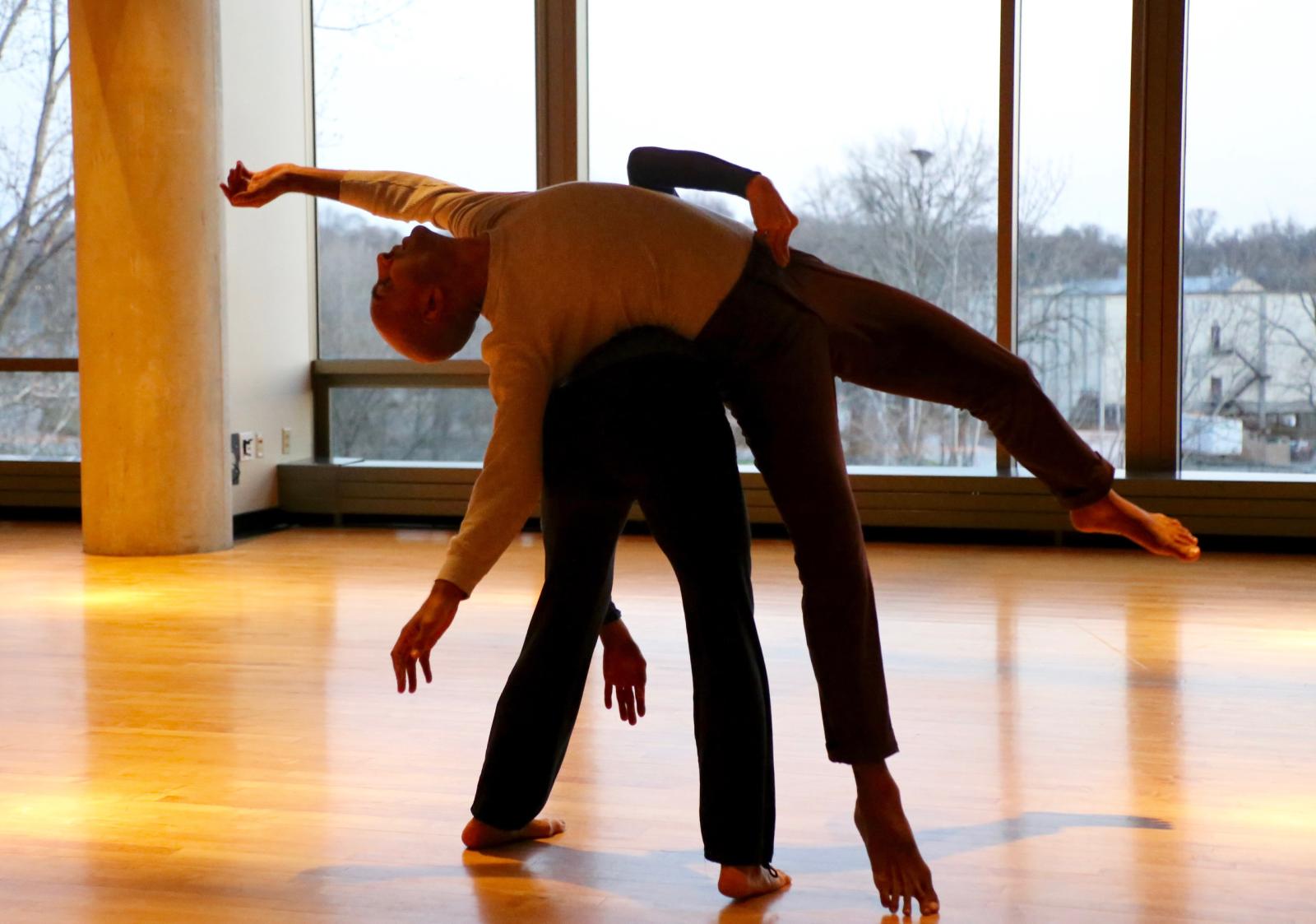 two dancers dancing in an open room with large windows behind them