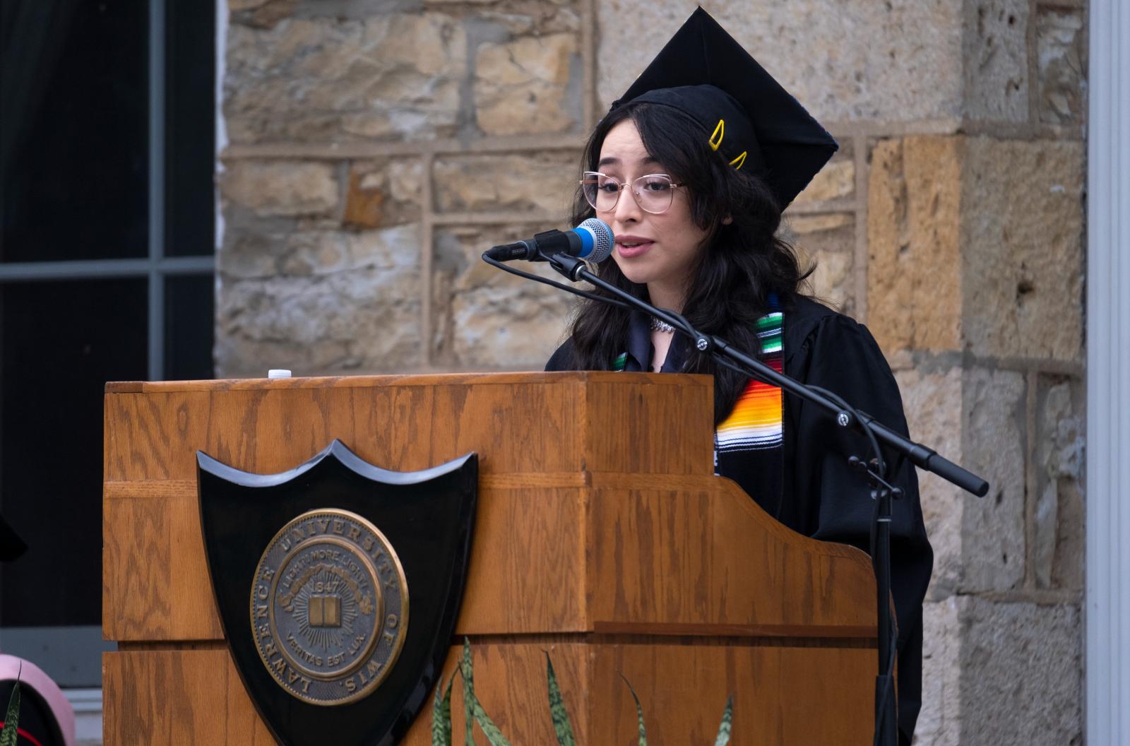 Samantha Torres is delivers her senior class speech at a podium wearing a graduation cap and gown.