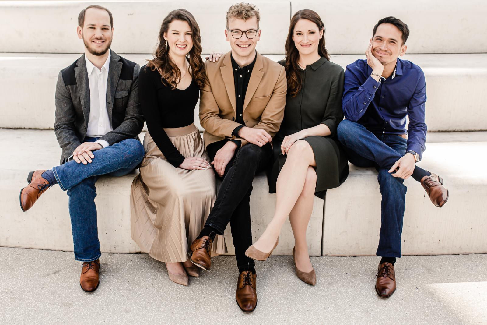 The five members of the Calmus Vocal Ensemble sit on the edge of a large cement stair.