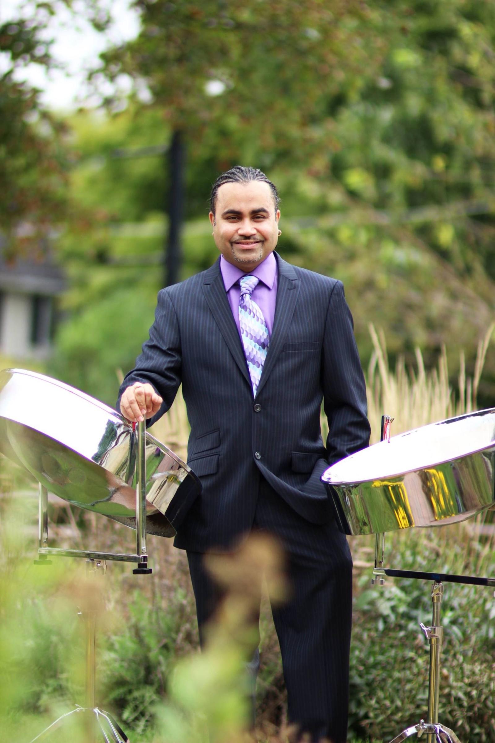 Musician Liam Teague stands outdoors with his steel drums.