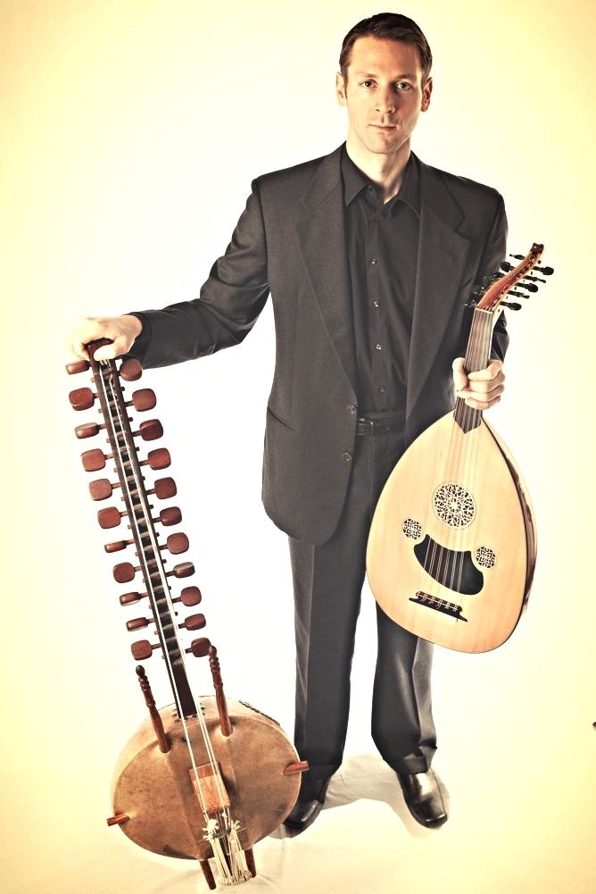 Kane Mathis stands holding his two instruments looking at the camera.