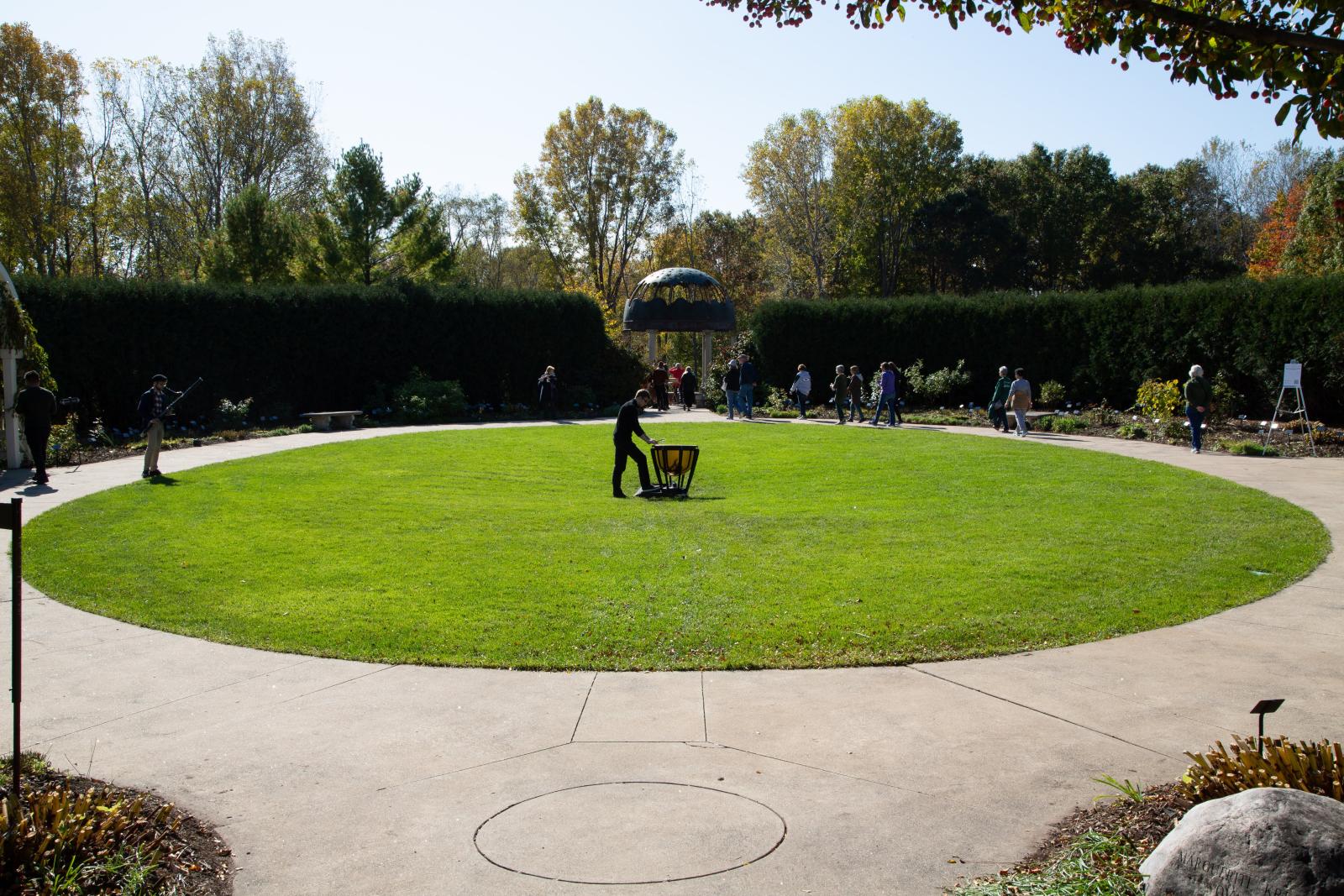 People playing instruments and walking around in a circular outdoor garden.