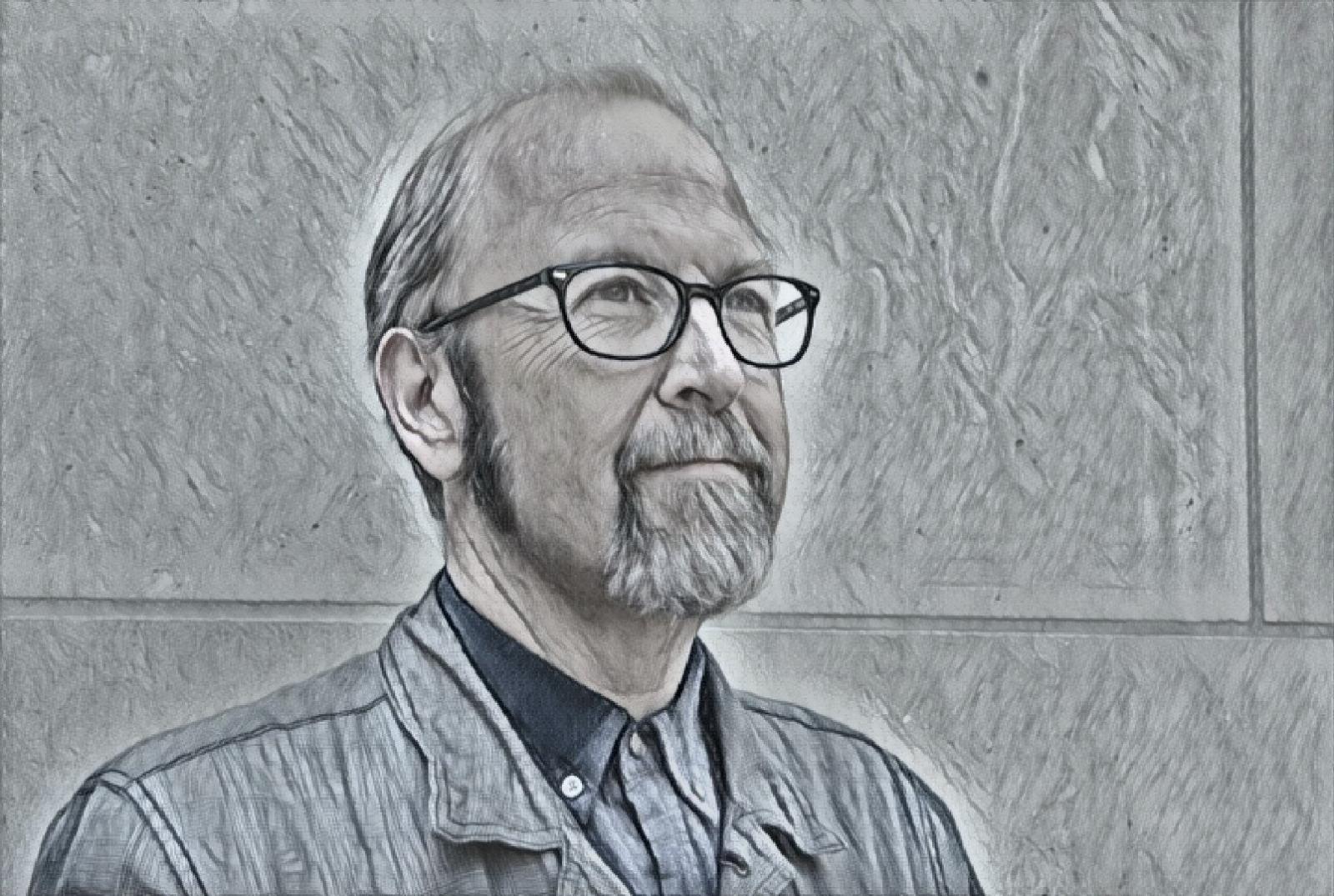 Headshot of a bespectacled man looking off camera and into the distance.