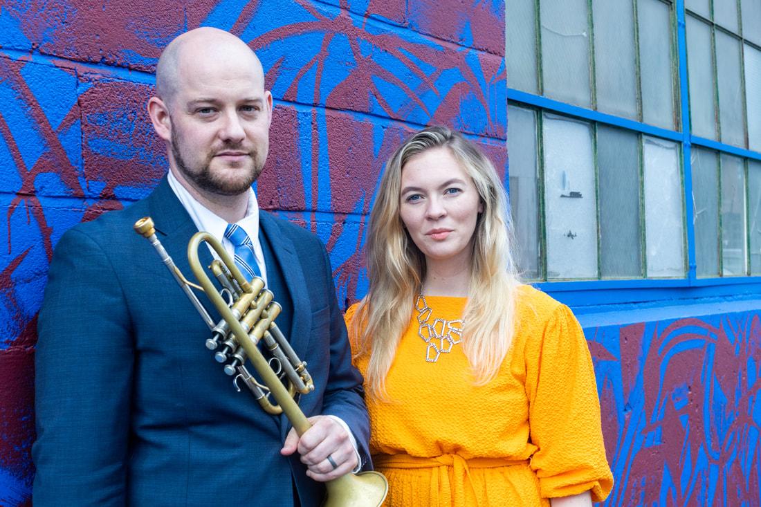 Man holding a trumpet and a woman standing next to him.