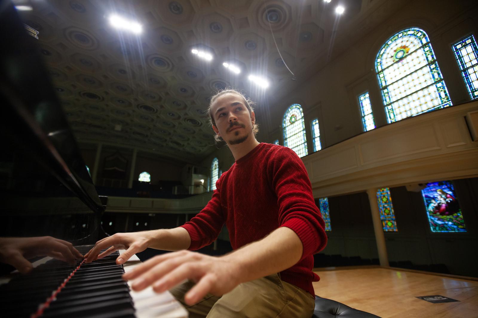 Bohdan Tataryn plays the piano with the Memorial Chapel windows in the background.