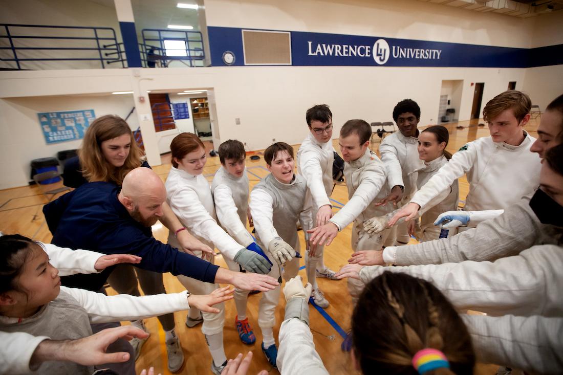 Coach Eric Momberg gathers his athletes in a huddle.