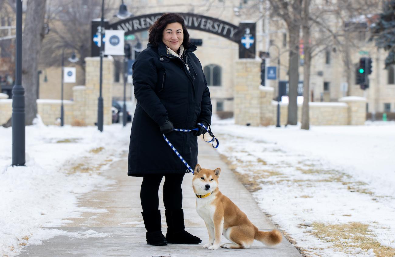 Monica Rico is joined by her dog, Connor, on the sidewalk with the Lawrence Arch in the background.