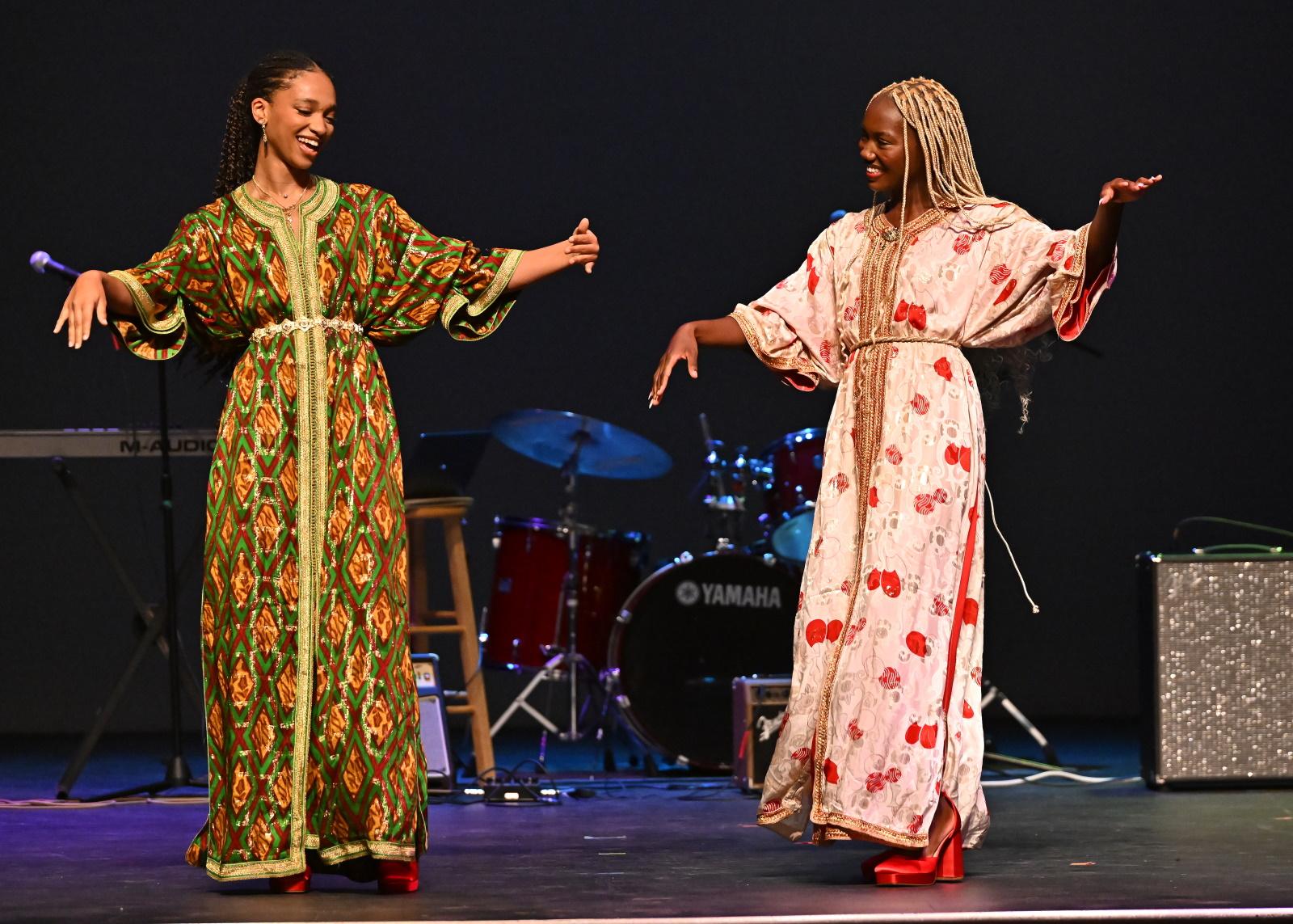 Two students smile at each other as they show fashions during Cabaret.