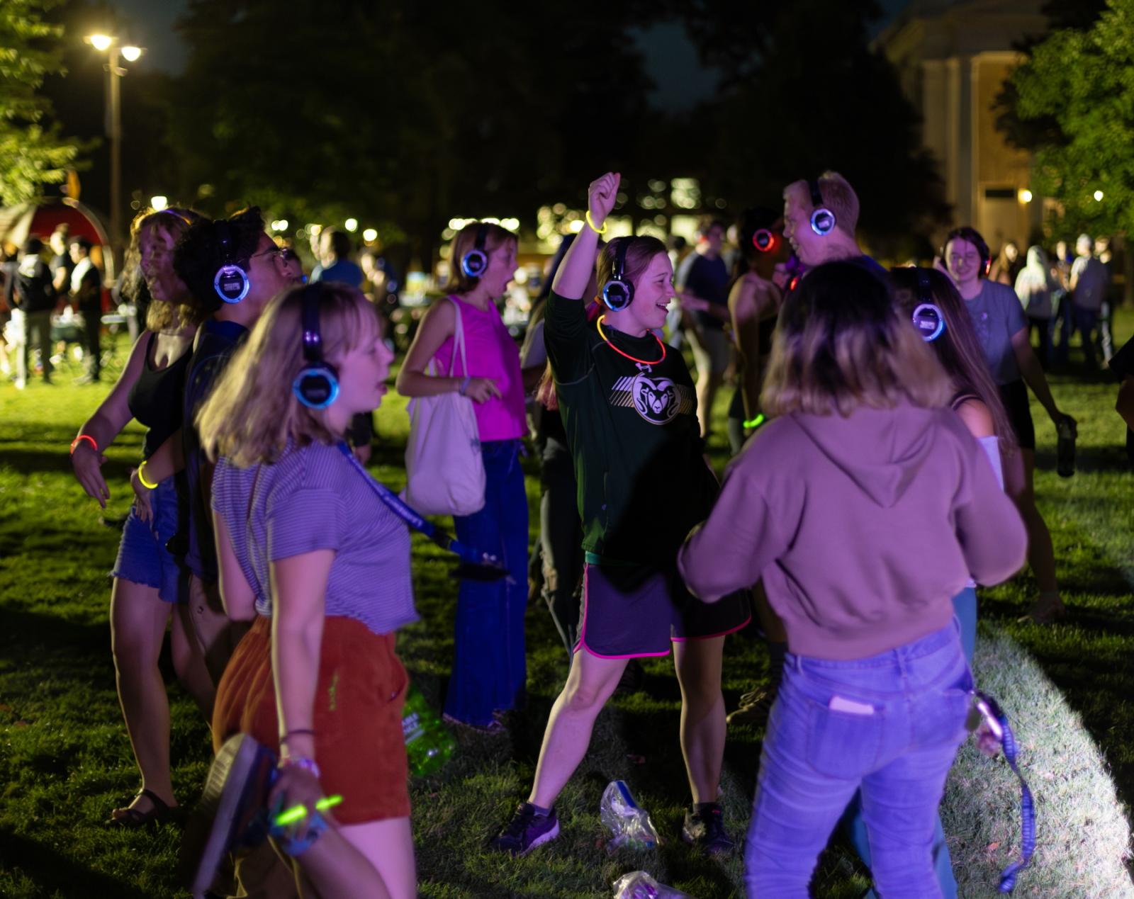Students dance together while listening to headphones as part of a silent disco event on Main Hall Green.