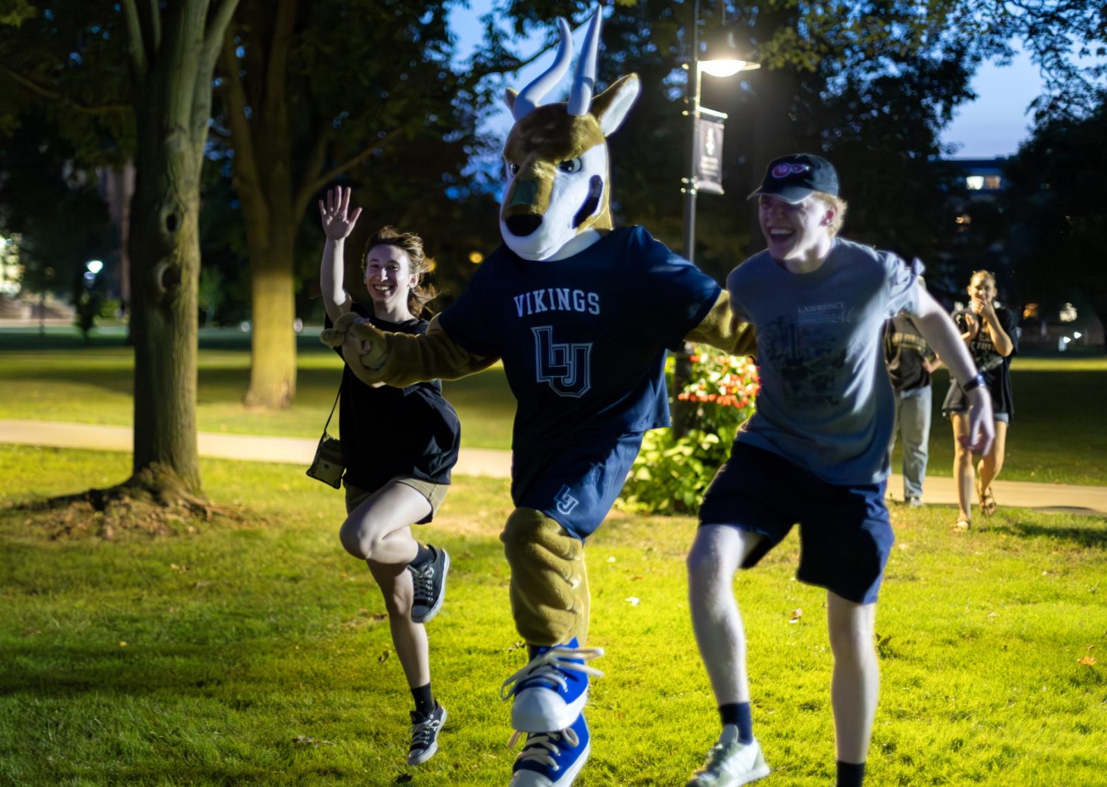 The mascot Blu joins two students at Blu's Bash on Main Hall Green.