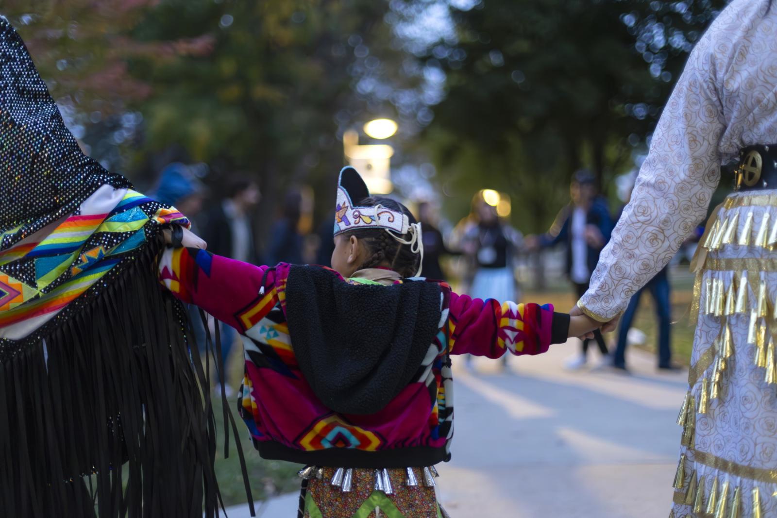 A child holds hands with other participants during the Indigenous Peoples' Day Celebration on Main Hall Green.