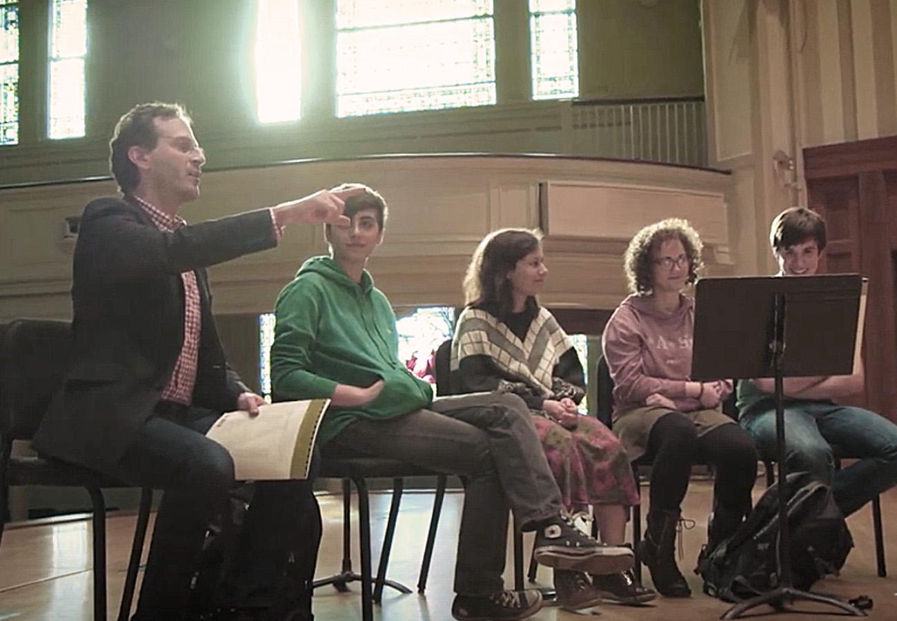 Michael Mizrahi instructing students on stage at Lawrence Memorial Chapel
