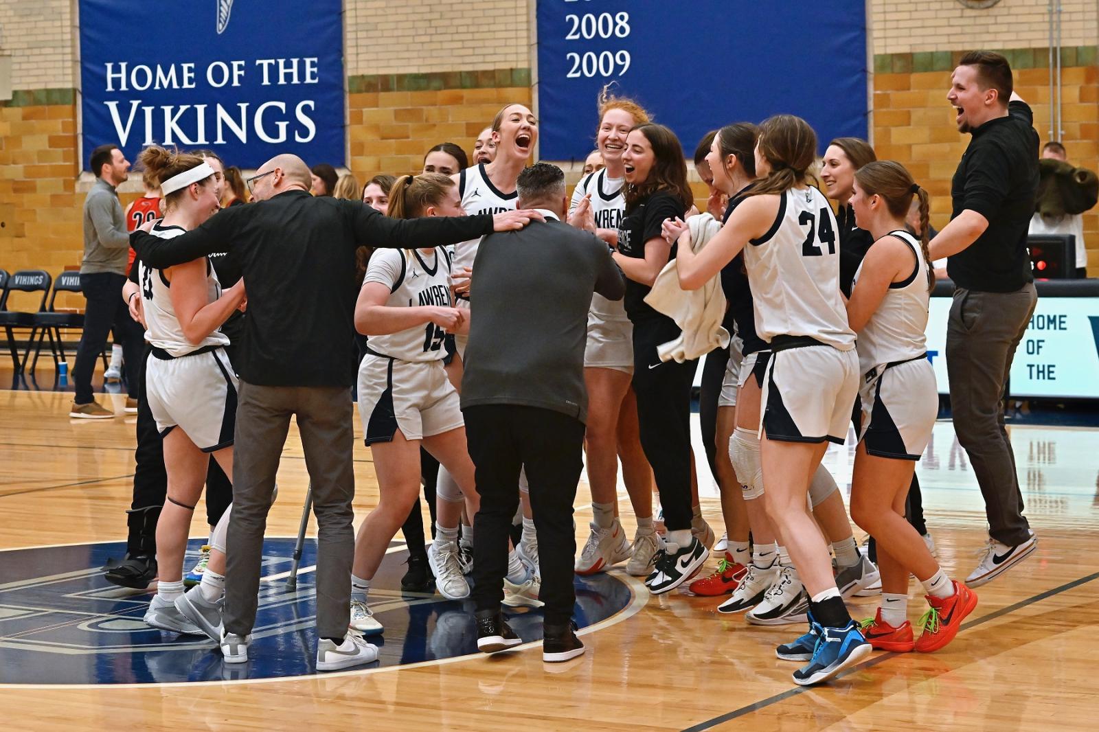 Players and coaches celebrate on the floor after the Vikings beat Ripon.
