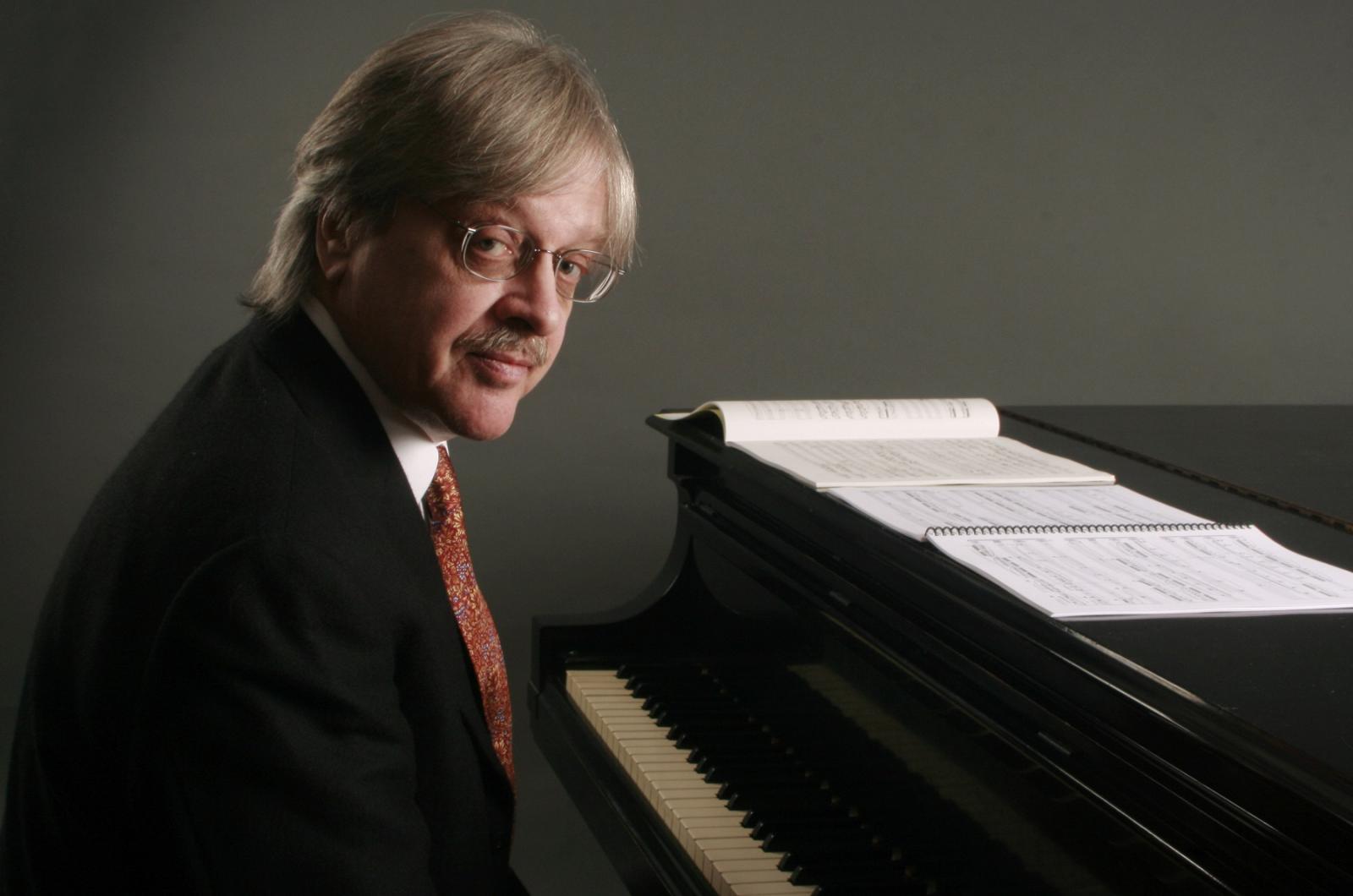 Fred Lerdahl poses for a photo at a piano.