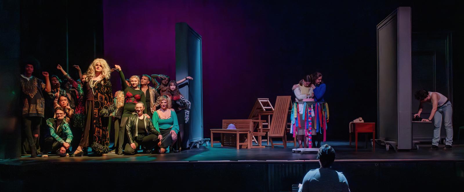 An ensemble of costumed performers on a stage divided into three sections.